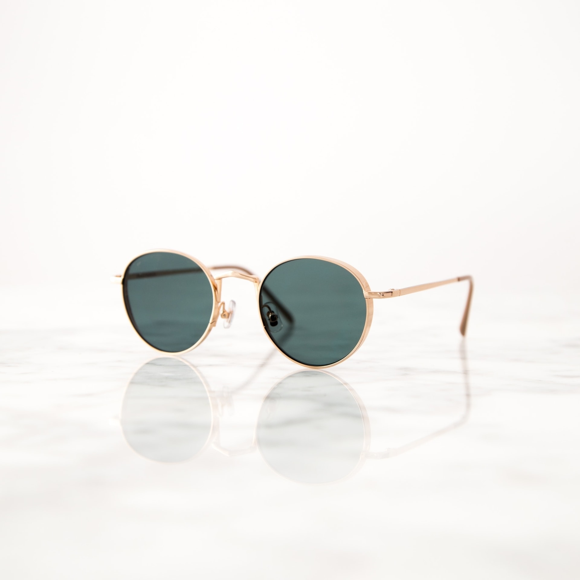 Gafas sol Gafas de sol con montura dorada sobre superficie de mármol reflectante