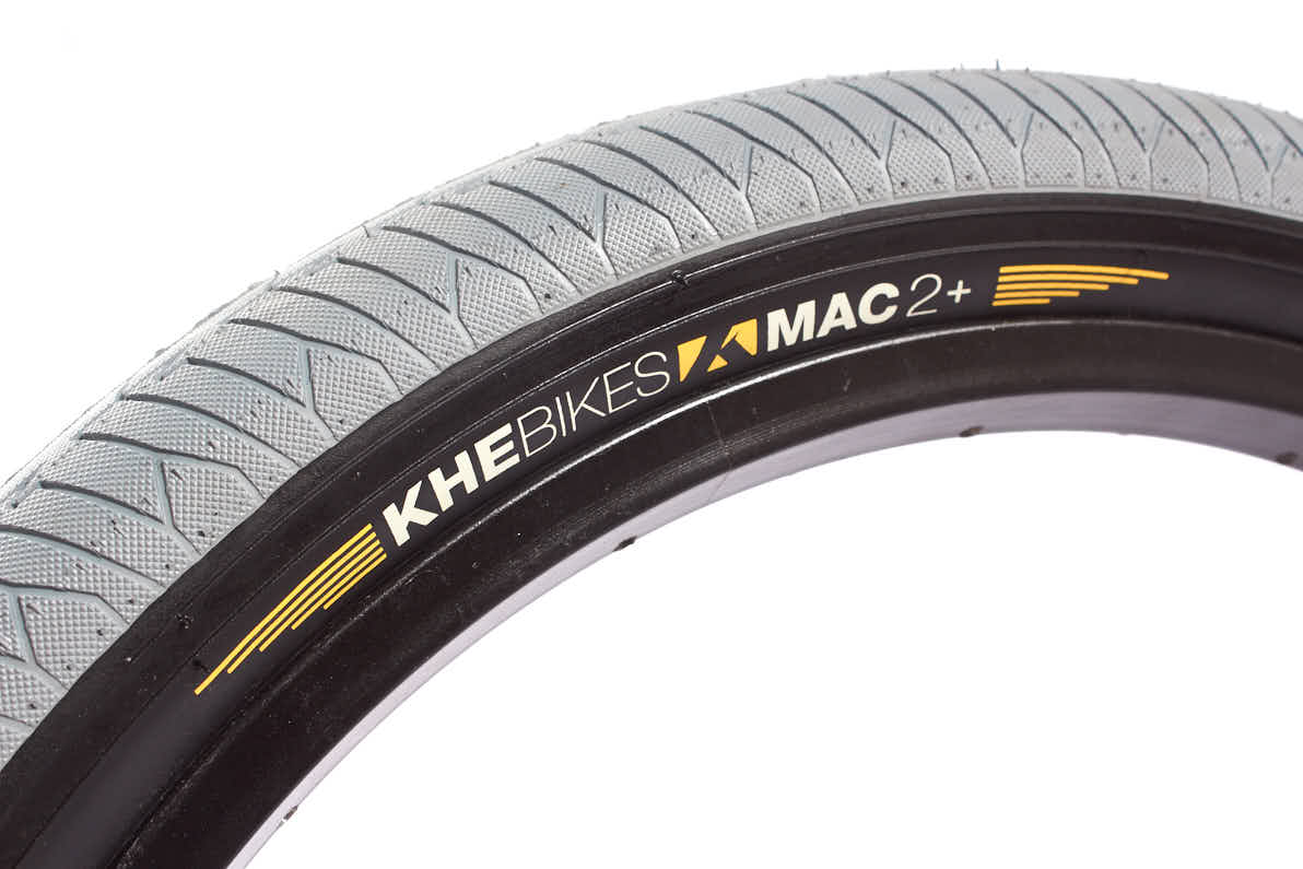 Grauer Reifen mit schwarzem Innenring und weiß,orangener KHEbikes MAC2+ Aufschrift  Grauer Reifen mit schwarzem Innenring und weiß,orangener KHEbikes MAC2+ Aufschrift